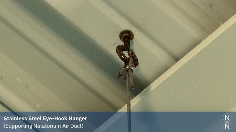 a corroded stainless steel eye hook hanger in a ceiling, creating a structural risk